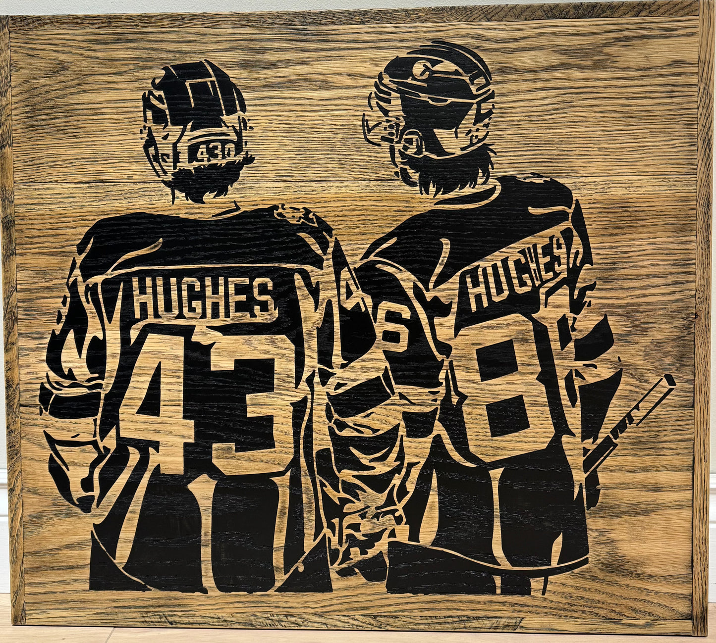 Wooden sign of image of Luke and Jack Hughes standing next to each other during the 2023 Stanley Cup Playoffs. 