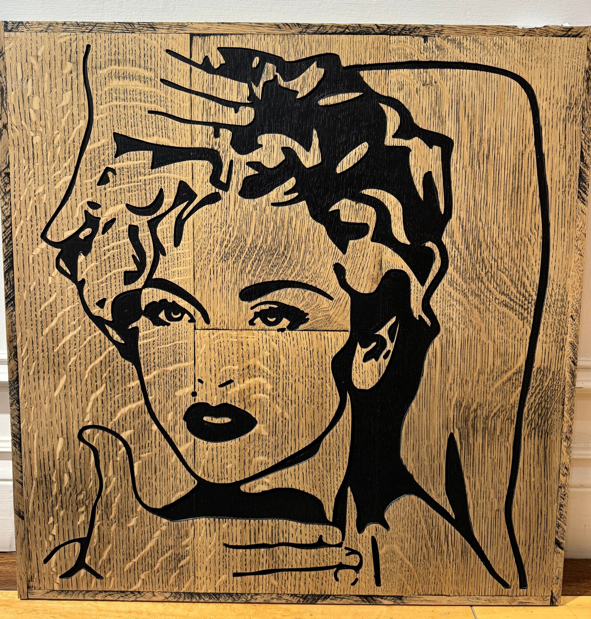 Wooden sign of Madonna framing her face using her hands as though she is "Voguing"